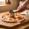 Ahşap saplı pizza ruleti ile fırından çıkmış pizzayı dilimleme